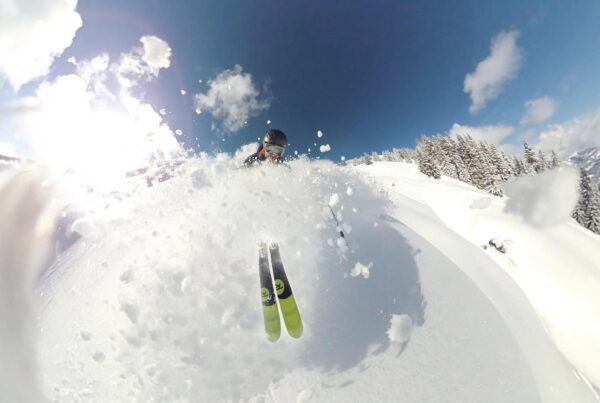 a skier bursting through bank of snow at the top of a mountain