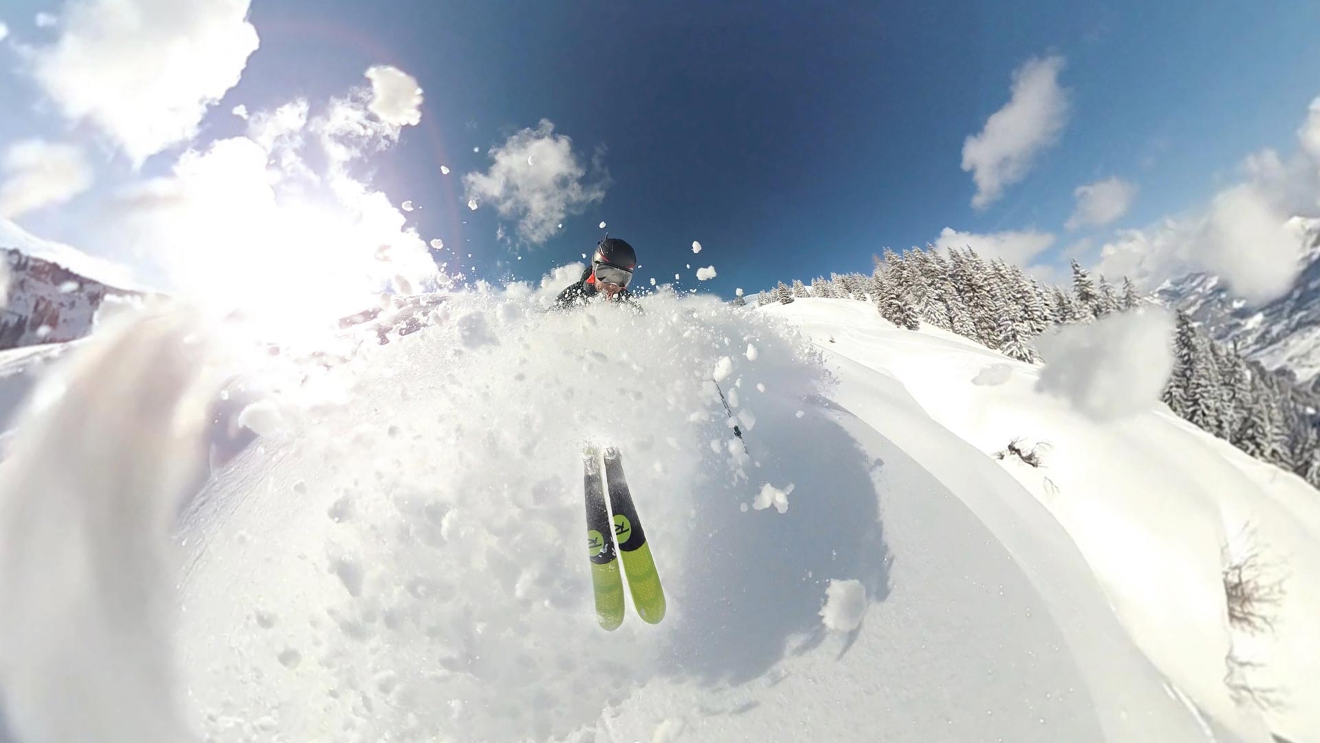a skier bursting through bank of snow at the top of a mountain